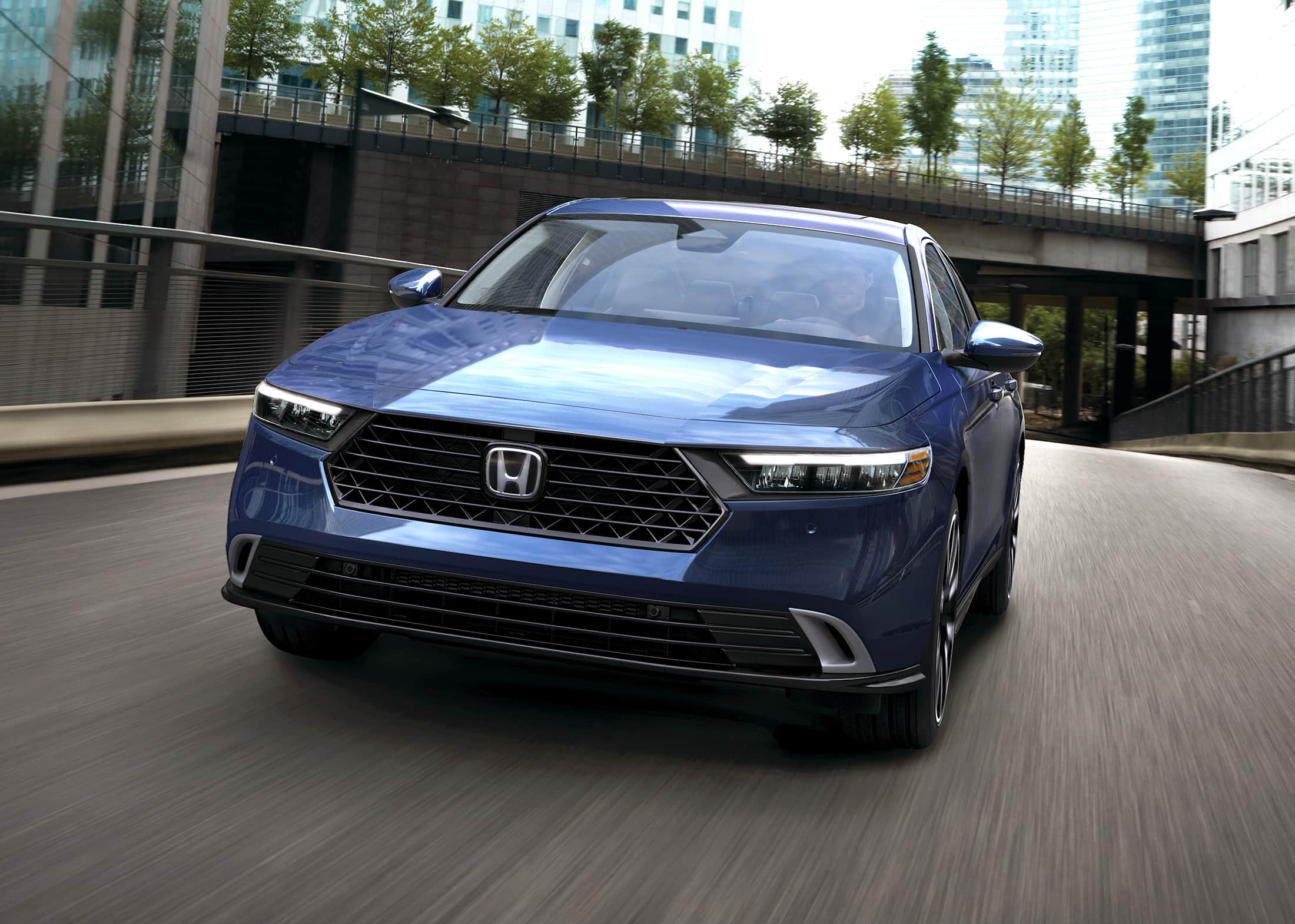 5/16 front driver-side view of the 2023 Honda Accord Touring Hybrid in Canyon River Blue Metallic, shown driving just after a freeway overpass.