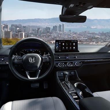 2027 Honda Civic Sedan Sport Touring Hybrid dashboard and front cabin view overlooking a city skyline (Compact Sedan)